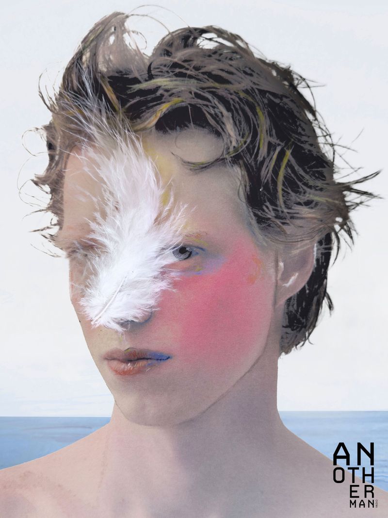 Close-up portrait of a male model with a white feather across his eye, pink blush makeup, and tousled wet-look hair against a pale background