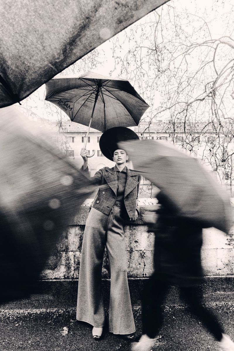 Model Jade Baya holding an umbrella in a tailored suit outdoors for T: The New York Times Style Magazine MENA by Avani Rai.