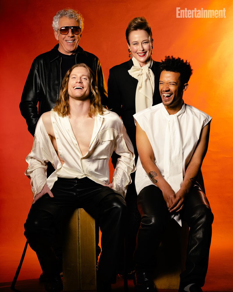 Portrait of four actors from The Vampire Lestat posing against a warm orange gradient background in stylish contemporary and vintage attire.