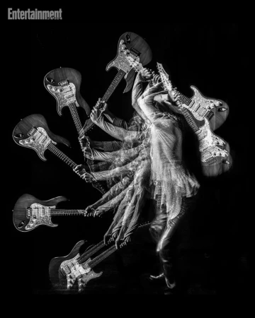 Monochrome multiple exposure photograph of a musician holding an electric guitar creating a radiating motion blur effect.