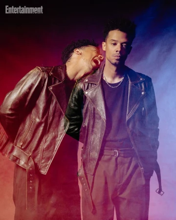Two exposure portrait of a man wearing a brown leather jacket and dark shirt against a red and blue lit studio background.