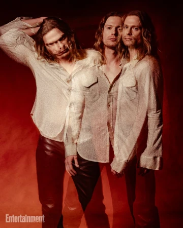 Multiple exposure portrait of a man with long hair wearing a patterned shirt and dark trousers against a red background