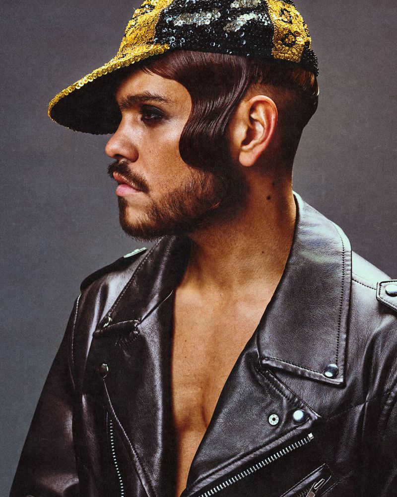 Profile portrait of a man wearing a black leather jacket and a gold sequin cap for Fault Magazine editorial