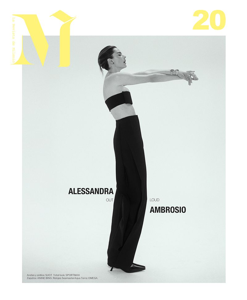 Alessandra Ambrosio models in a black strapless top and wide-leg pants, posing against a stark white backdrop for a minimalist fashion shot.