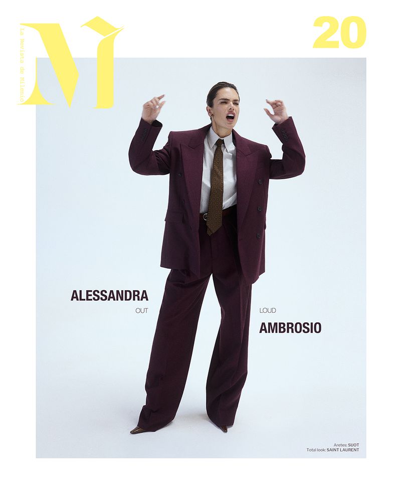 Fashion editorial shot of a model in a dark red suit and tie against a white backdrop for a magazine cover, minimalist style.