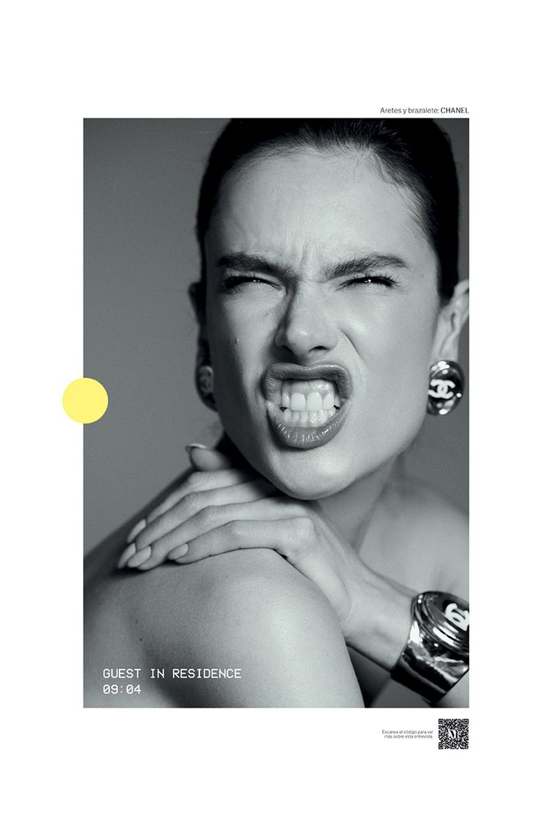 Close-up shot of a woman with a scrunched face and visible teeth wearing Chanel earrings and a silver cuff bracelet in a studio environment.