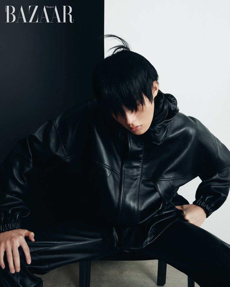 Model in black leather jacket and pants posed against a split black and white studio background