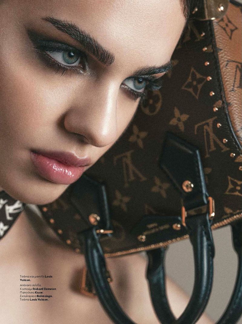 Close-up portrait of a woman with dramatic eye makeup holding a monogram handbag for InStyle Greece You Don't Know Me editorial