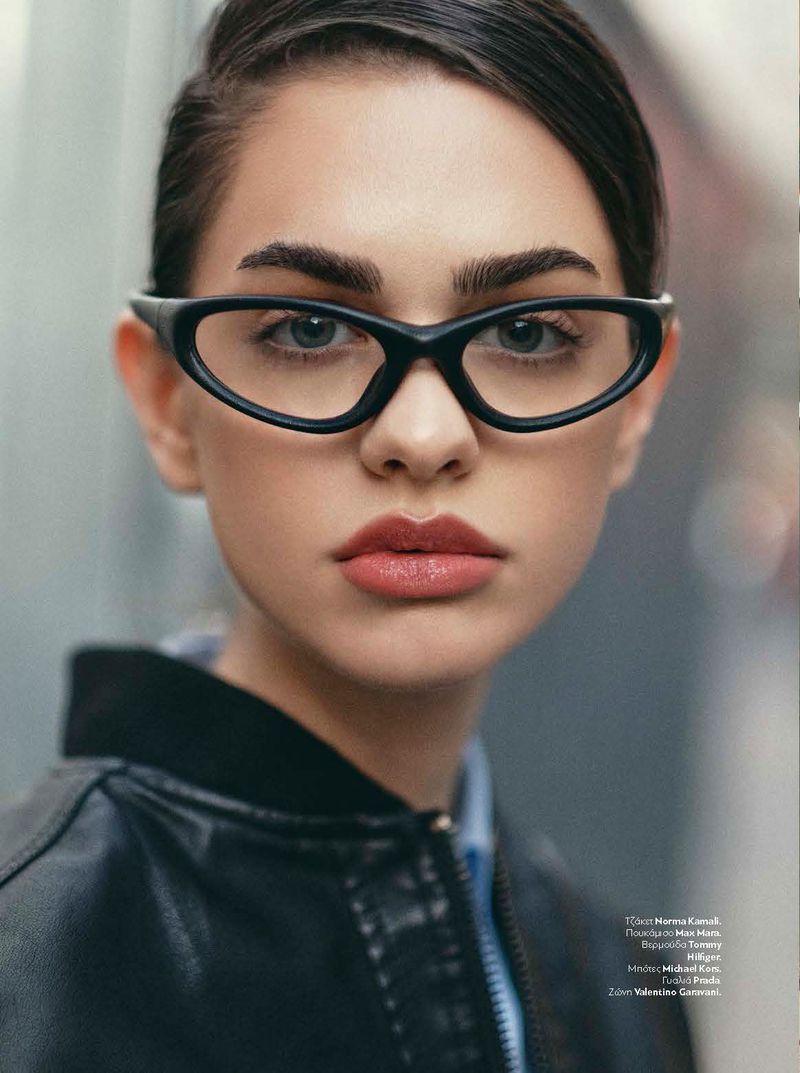 Close-up portrait of a woman wearing black cat-eye glasses and a black jacket for InStyle Greece You Don't Know Me editorial