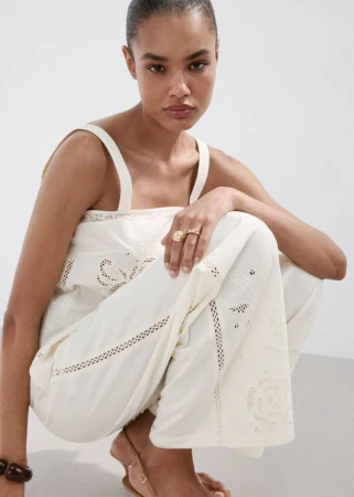 Model wearing a white embroidered top and trousers crouching against a white background for Mango S/S 26