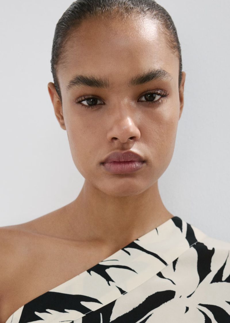 Close up beauty portrait of a model wearing a black and white patterned top against a neutral background