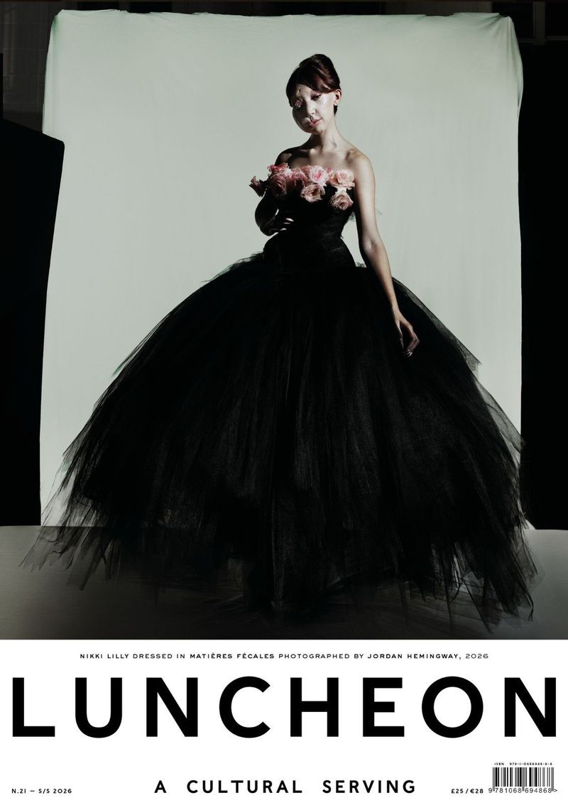 Woman in a voluminous black gown adorned with pink roses standing against a white seamless backdrop for Luncheon Magazine