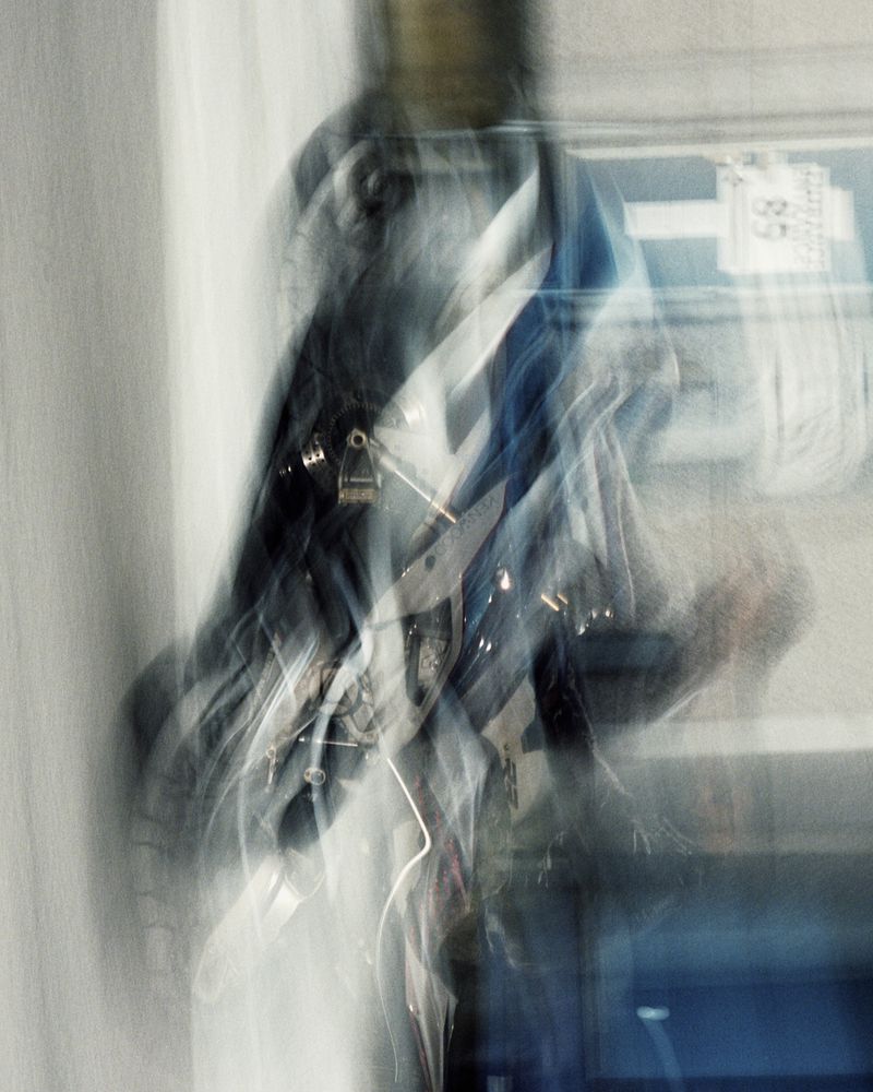 Abstract, blurred long exposure of a person in dark clothing, creating a sense of motion and anonymity in an urban environment.