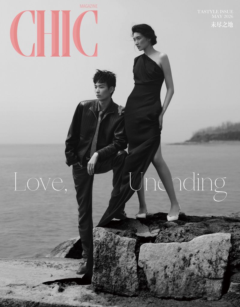 Magazine cover featuring an adult male and an adult female fashion models posing outdoors on a rocky surface near the ocean.