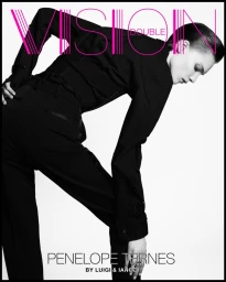 Model Penelope Ternes wearing a black button-down shirt and trousers against a white seamless backdrop.