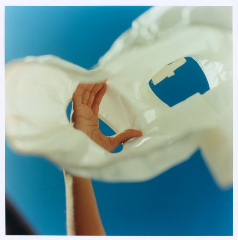 Hand holding a white garment against a bright blue sky for Maje x Blanca Miro campaign