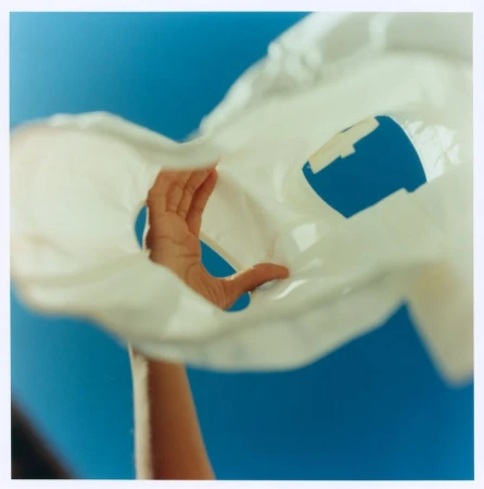 Hand holding a white garment against a bright blue sky for Maje x Blanca Miro campaign