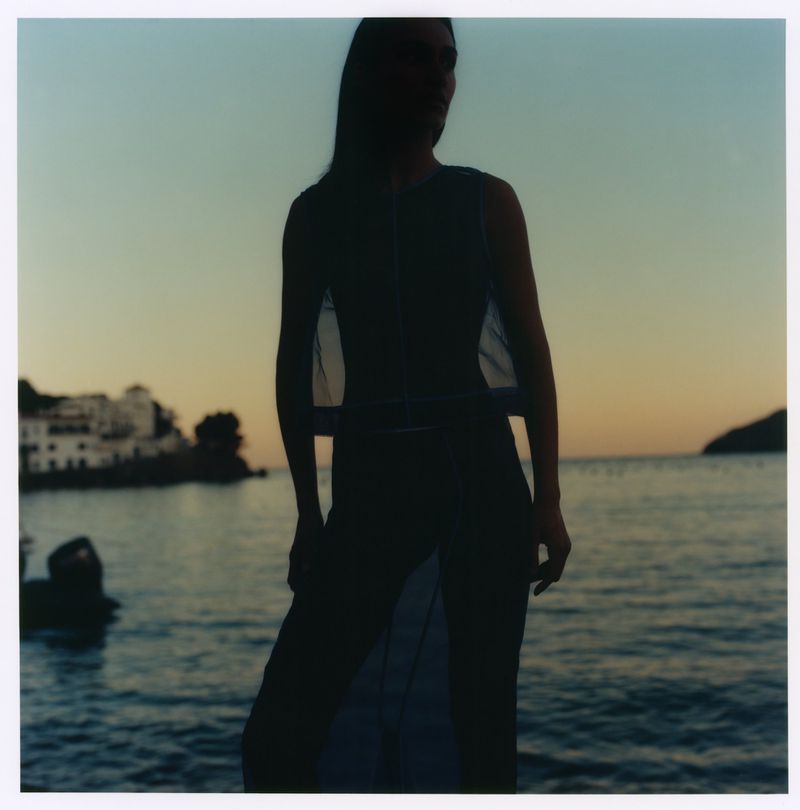 Silhouette of a woman standing by the water at dusk for Maje x Blanca Miro, captured by photographer Martin Gatti.