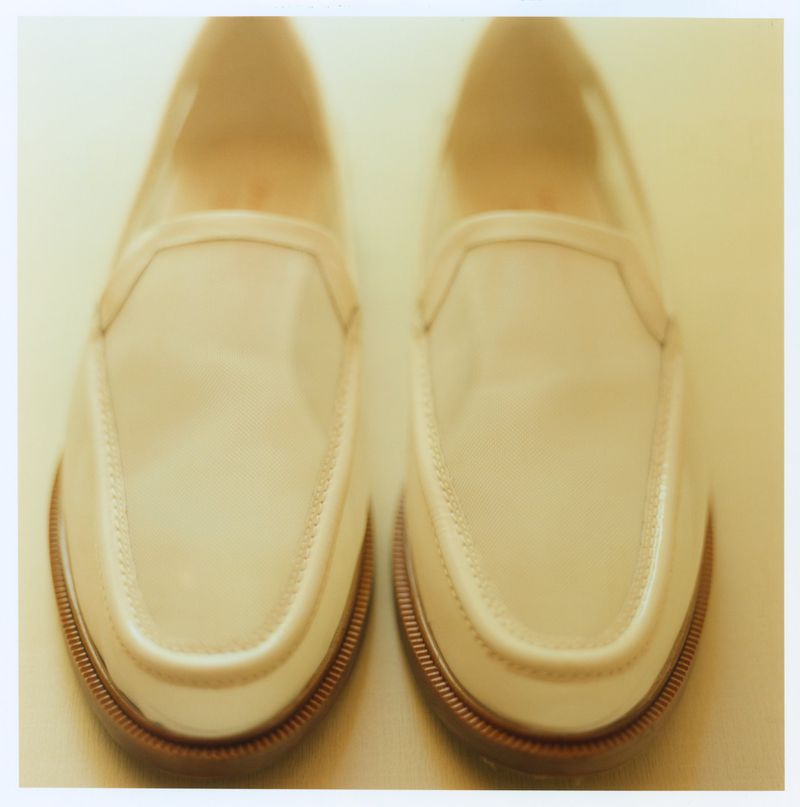 A pair of cream colored slip-on loafers photographed from a top-down perspective against a light background.