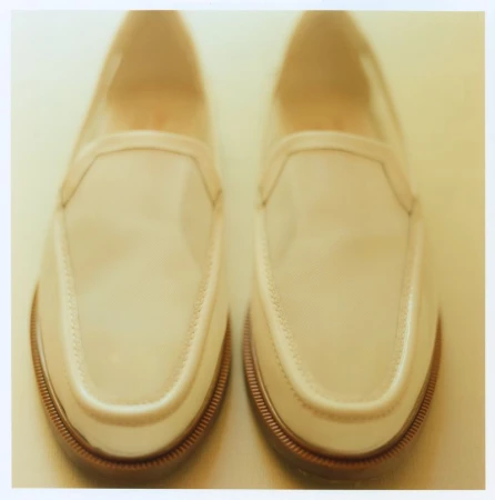 A pair of cream colored slip-on loafers photographed from a top-down perspective against a light background.