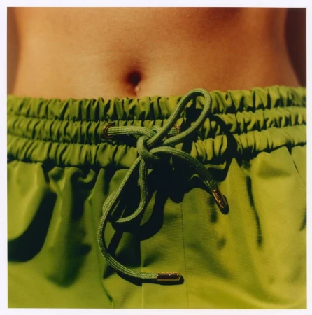 Close-up of olive green drawstring shorts with a tied waist and exposed midriff photographed by Martin Gatti for Maje x Blanca Miro.