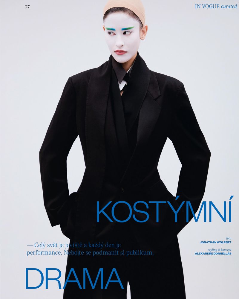 Model in black blazer and trousers with white painted face makeup against a pale background for Vogue Czechoslovakia