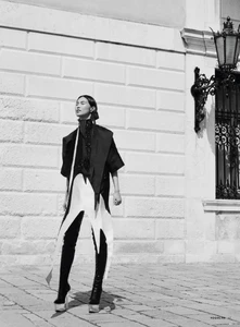 Model in architectural monochrome outfit with platform boots standing against a classical stone building exterior.