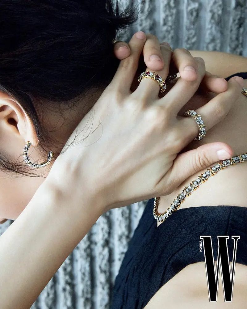 Close-up of a model wearing diamond rings, hoop earrings, and a tennis necklace with a black top for W Korea Traces of Light editorial.