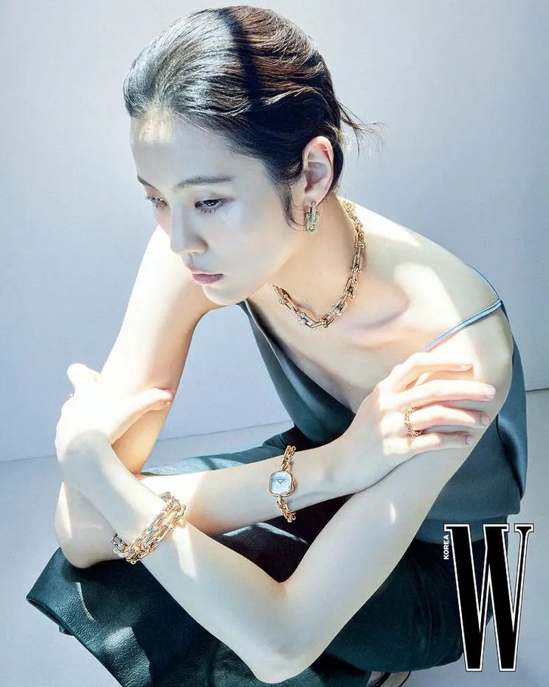 Woman wearing jewellery and a watch posing against a white studio background for W Korea Traces of Light editorial