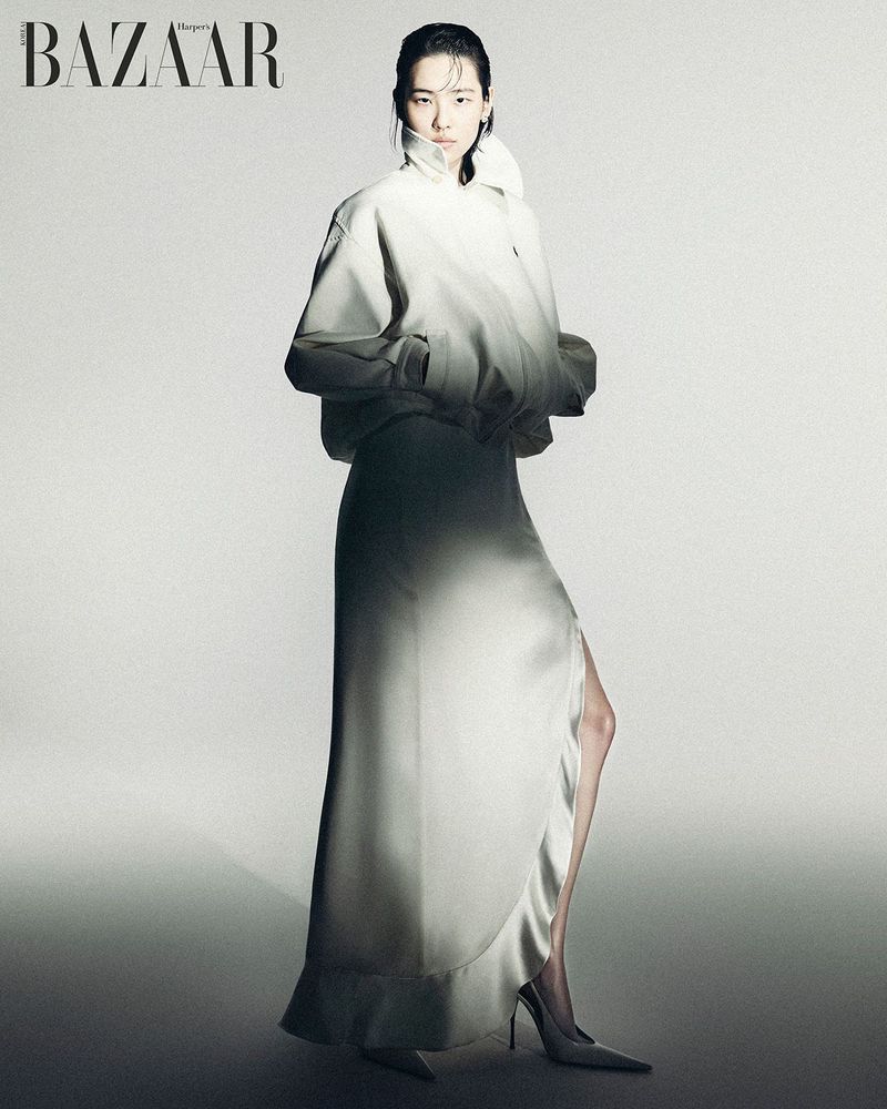 Model wearing a white jacket and long skirt posing against a light grey seamless studio background for Harper's Bazaar Korea