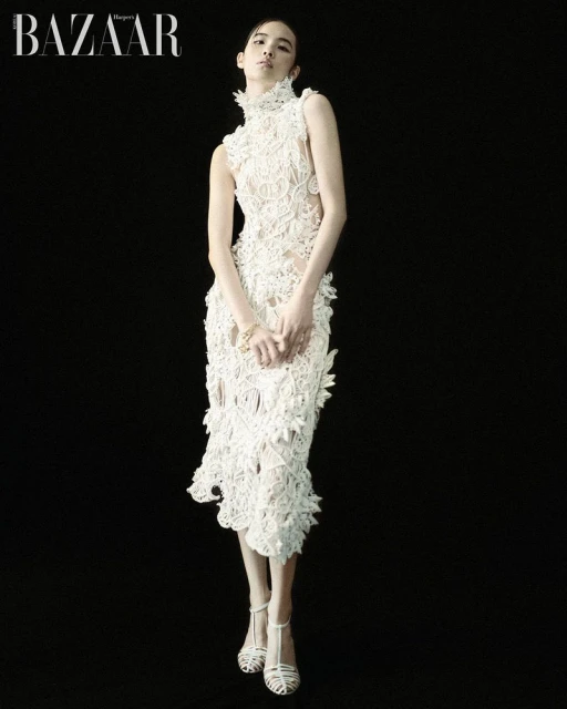 Model wearing a white lace dress standing against a solid black background for Harper's Bazaar Korea editorial
