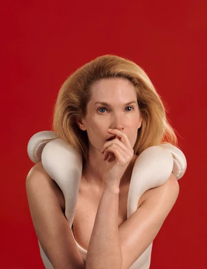 Model Birte Carolin Von Knoblauch posing in a white sculptural garment against a bold red background for Numero China.