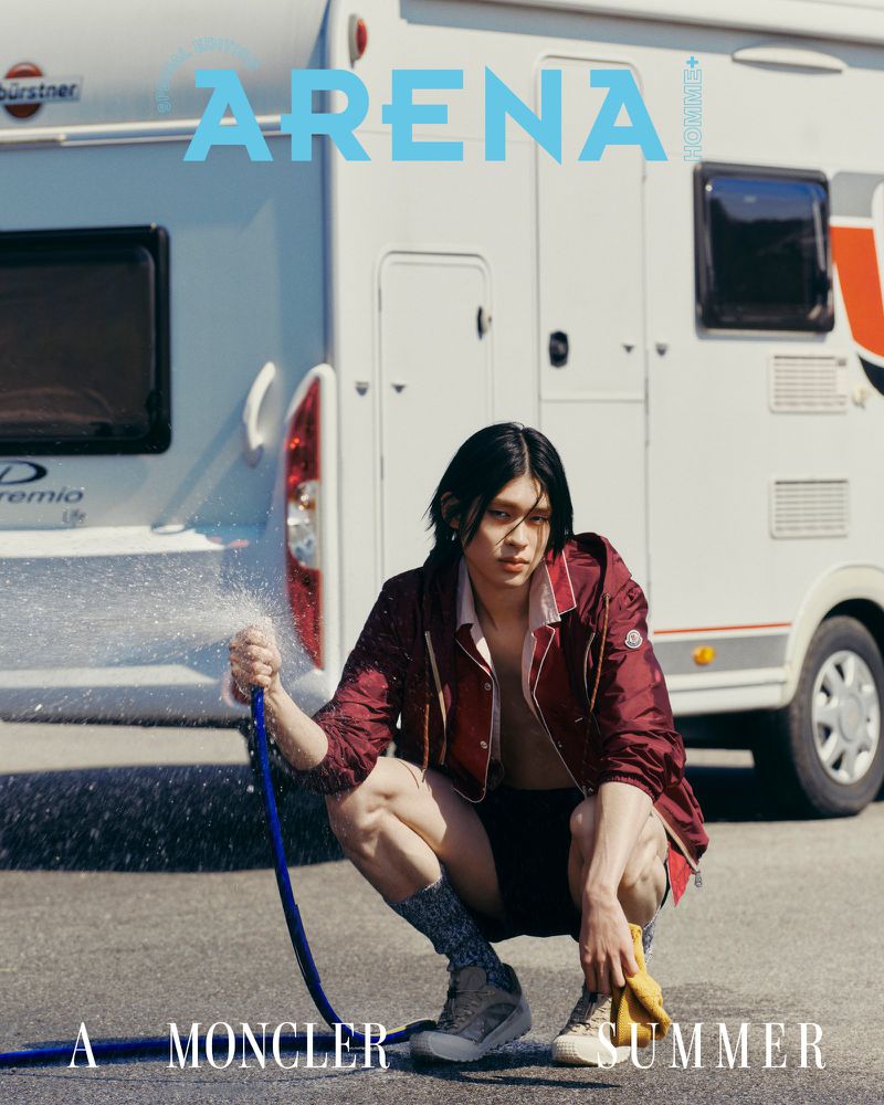 Model squatting while spraying water from a hose in front of a camper van for an Arena Homme Korea editorial feature.