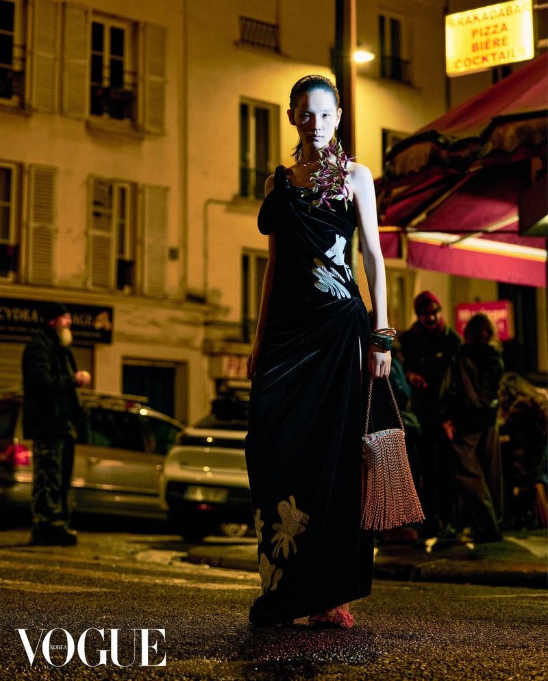 Model Song Ah Woo in a black velvet gown holding a fringed handbag on a city street at night for Vogue Korea
