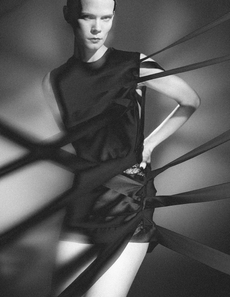 Model Irina Kravchenko in a black dress entangled with dark ribbons for L'Officiel Italia