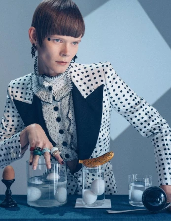 Model in polka dot blazer posing behind glass containers filled with water and eggs for L Officiel Italia editorial