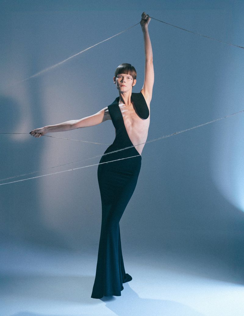 Model Irina Kravchenko in a black dress posed with strings like a marionette for L'Officiel Italia project Manifeste du Surrealisme