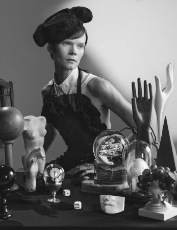 Model Irina Kravchenko wearing a sculptural dark hat among surreal props in a black and white editorial by Frederico Martins