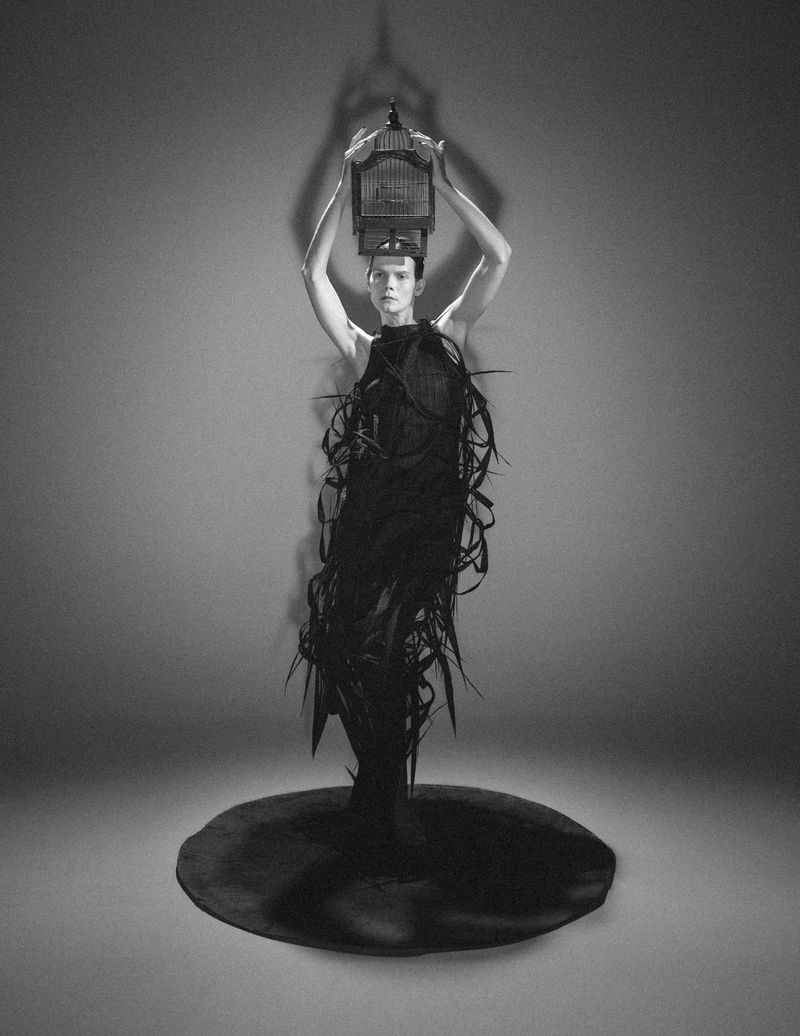 Model Irina Kravchenko holding a birdcage above her head in a monochrome fashion editorial photographed by Frederico Martins.