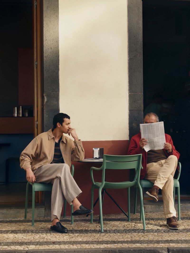 Two men sitting outside at a cafe table on a patterned stone pavement for Mr Porter Off Duty campaign