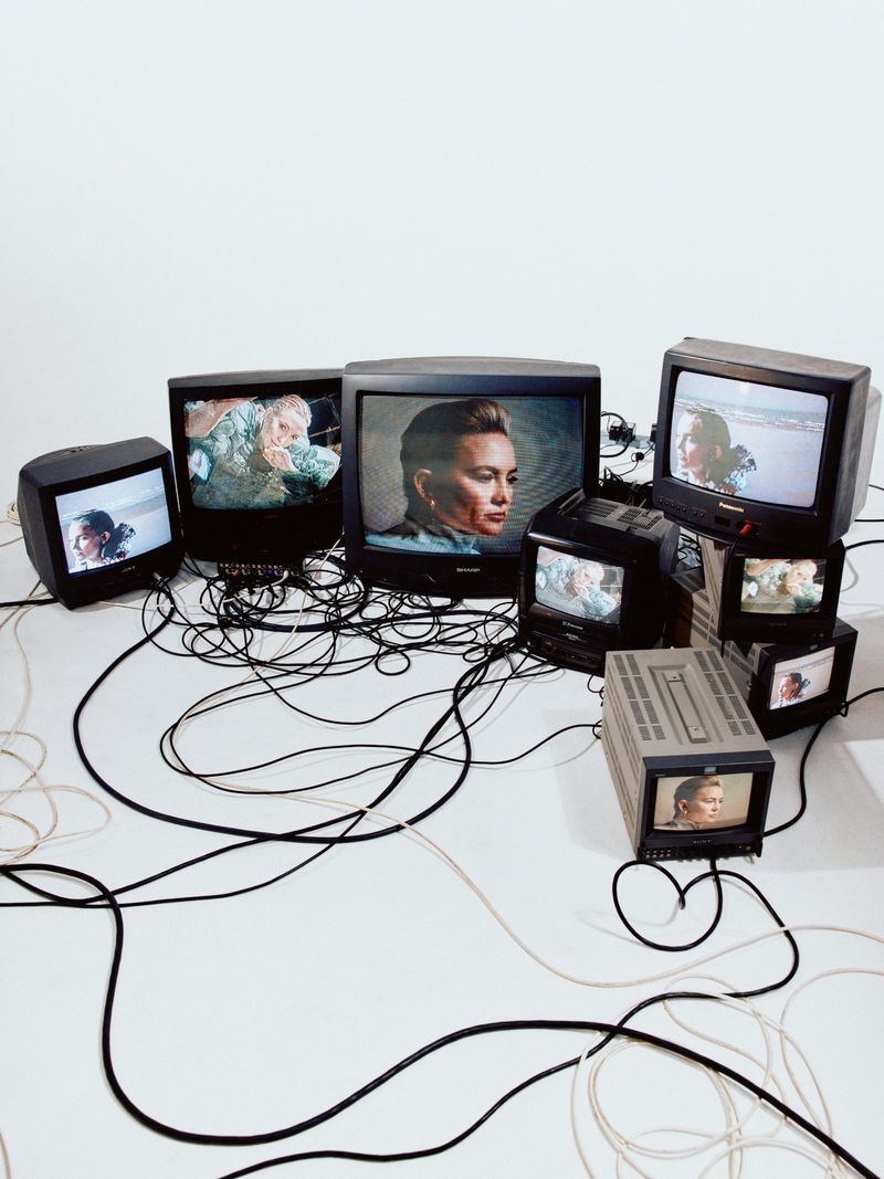 An arrangement of vintage cathode-ray tube televisions displaying portraits of Kate Hudson against a white seamless background