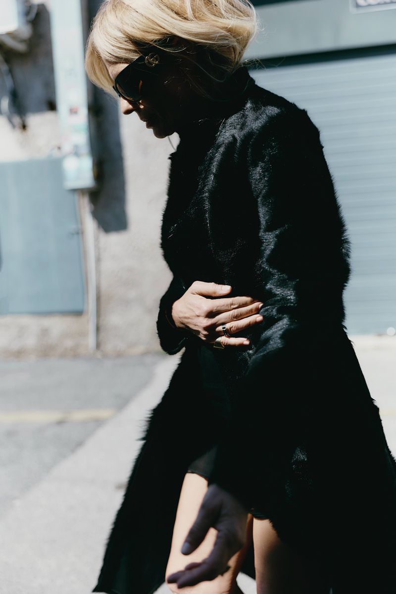 Isabella Ferrari wearing a black coat and sunglasses walking outdoors for L'Officiel Italia editorial