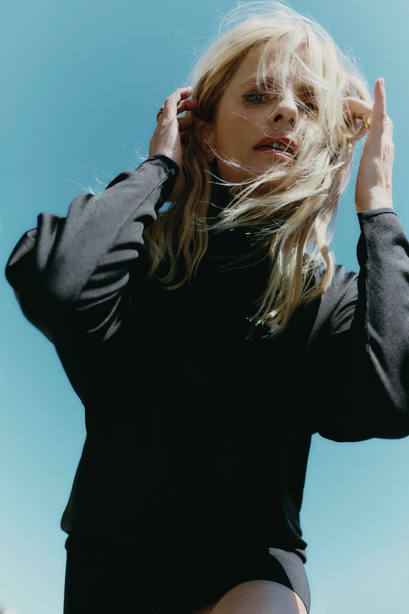 Isabella Ferrari wearing a black turtleneck against a clear blue sky for L'Officiel Italia editorial photography.