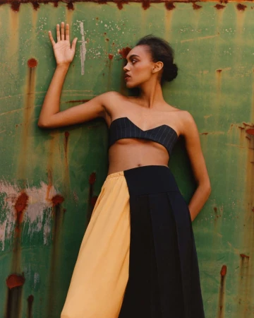 Model Bebe Parnell leaning against a weathered green metal wall for the Present Space project