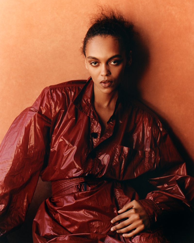Model Bebe Parnell in a glossy burgundy jacket against a warm textured background for Present Space project