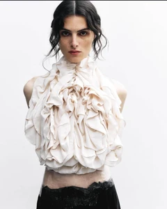Model wearing a heavily ruffled white top against a clean white studio background for Exhibition Magazine.
