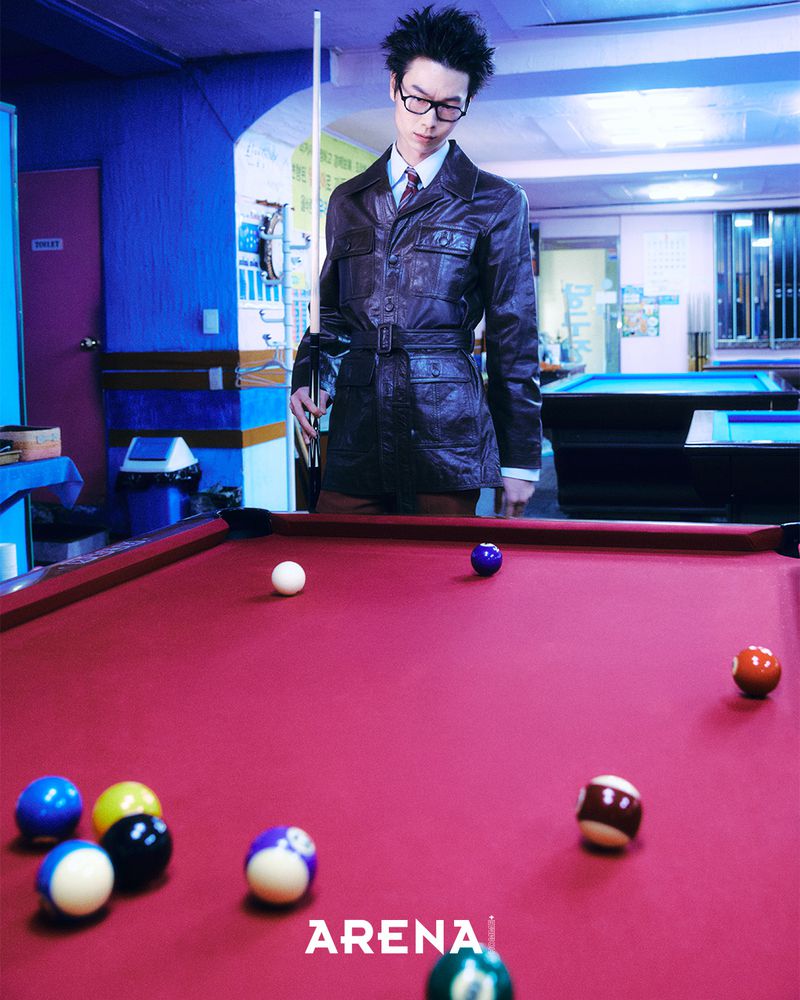 Model Tenny Suh holding a cue stick in a brown leather jacket by pool table for Arena Homme Plus Korea project Chalk & Cheat