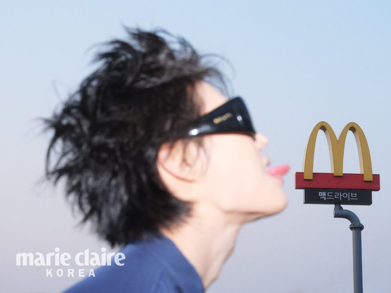 Motion-blurred profile of person in dark sunglasses sticking out tongue near McDonald's sign