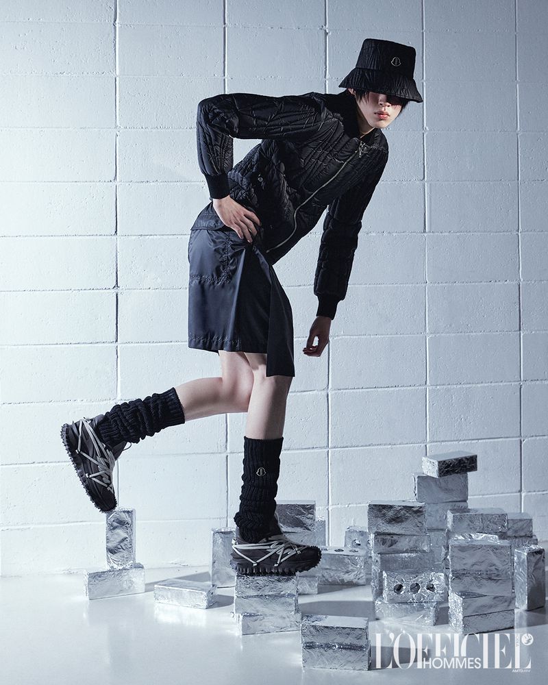 Model in black puffer jacket and bucket hat stepping on silver foil bricks in an editorial shot for L'Officiel Korea.