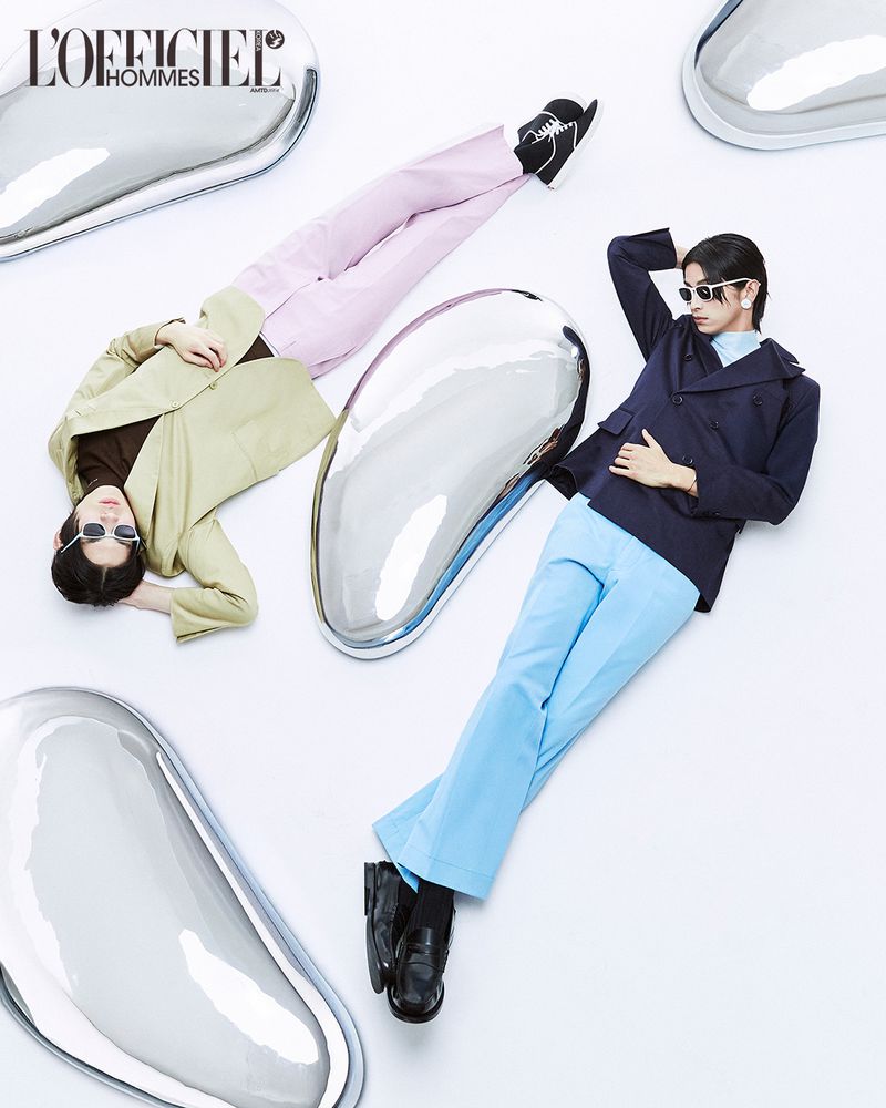 Two male models posing on a white seamless backdrop with reflective chrome puddle props for L'Officiel Korea Duo project.